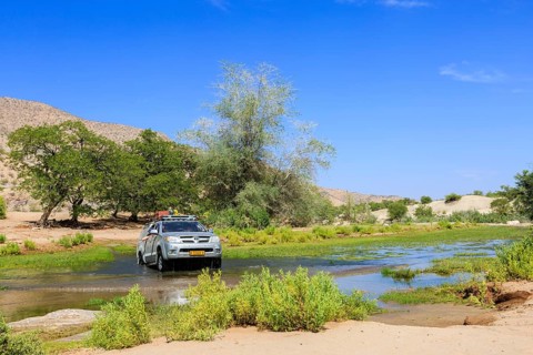 Off-road vehicle drives through Hoanib River