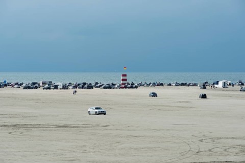 Cars parked on wide sandy beach