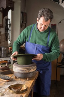 Hatter pushing dry wool felt hat into edge mold