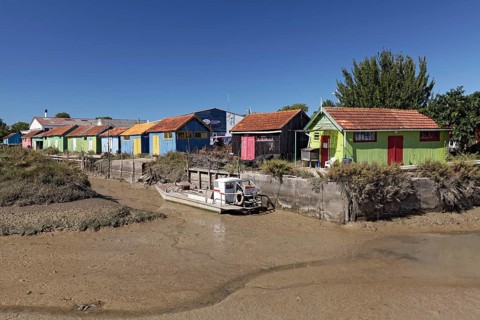 Colorful huts of oyster farmers on a channel at low tide