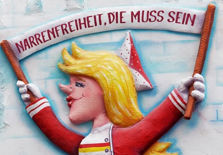 Papier mache figure holding carnival banner