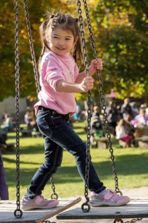 Eurasian girl standing on swing