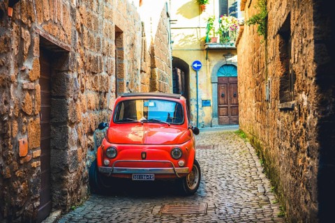 Old red Fiat 500 parked in a narrow alley