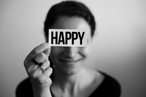 Portrait of a laughing woman holding a card with inscription Happy