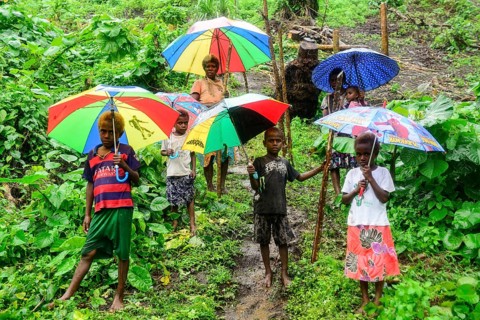 Native women with children with colourful umbrellas in the rain in the village of Rangsuksuk