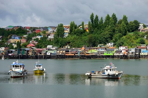 Fishing boats anchoring in front of colorful stilt houses