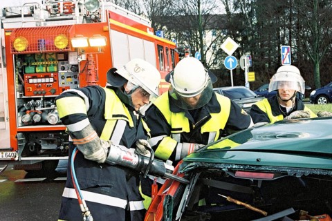 Firemen at traffic accident using Jaws of Life to rescue trapped car driver