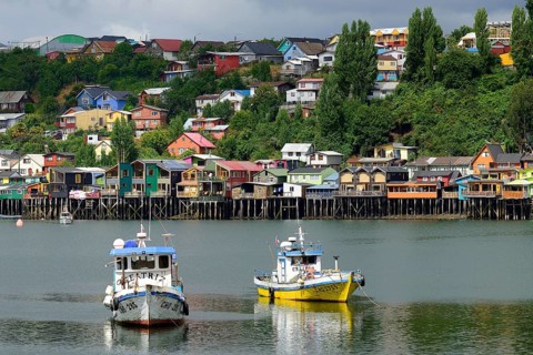 Fishing boats anchoring in front of colorful stilt houses