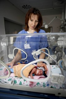 Nurse at incubator with newborn baby