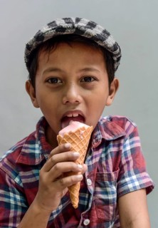 Boy with shirt and flat cap eating ice cream