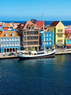 Old sailing ship in front of historic buildings in Dutch-Caribbean colonial style