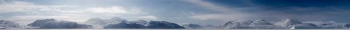 Panoramic view of snow-covered mountains seen from a frozen fjord