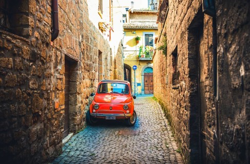 Old red Fiat 500 parked in a narrow alley