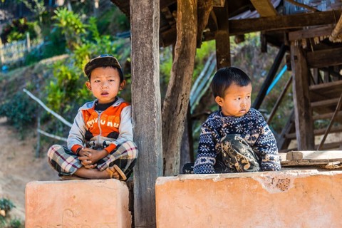 Two little boys sitting at log cabin