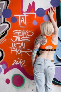 Young blond tattoo model posing at graffiti wall