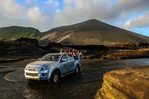 Jeep crosses river below volcano Yasur