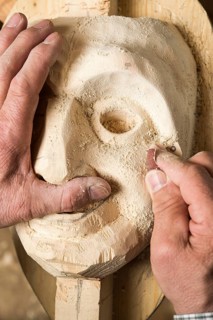 Sanding the face of a wooden mask
