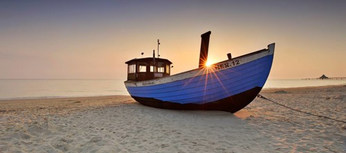 Fishing boat on beach at sunrise
