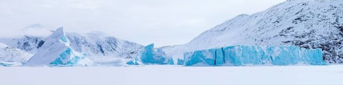 Panoramic view of snow-covered mountains seen from a frozen fjord