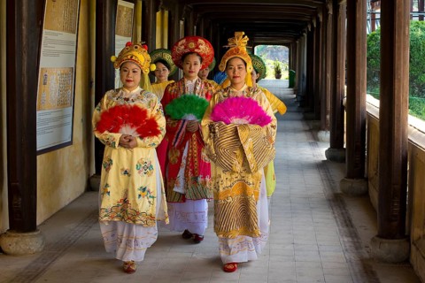 Vietnamese extras in traditional robes walking through imperial palace Hoang Thanh