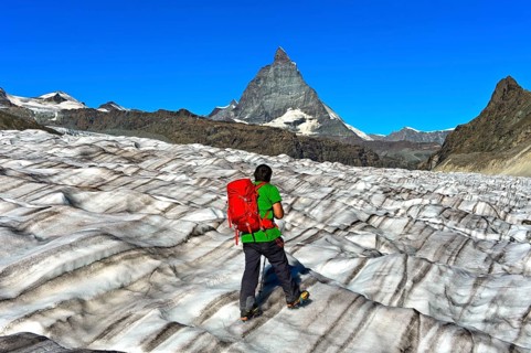 Hiker looks over the furrowed surface of the Gorner Glacier onto the Matterhorn
