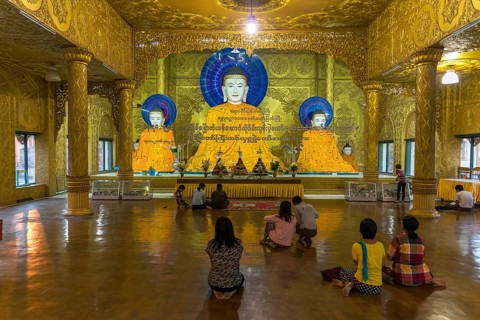 Religous people praying in front of Buddha statues Shwemokhtaw Pagoda
