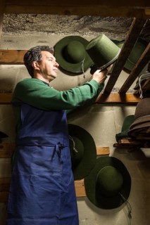 Hatter placing wool felt hat with shaping cord to dry on wooden boards in drying room