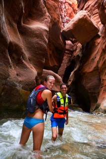 Young couple under big rock at the canyon of Wadi Mujib
