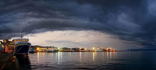 Harbour and Queens Wharf illuminated at sunset with dark storm clouds