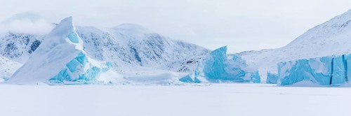 Panoramic view of snow-covered mountains seen from a frozen fjord