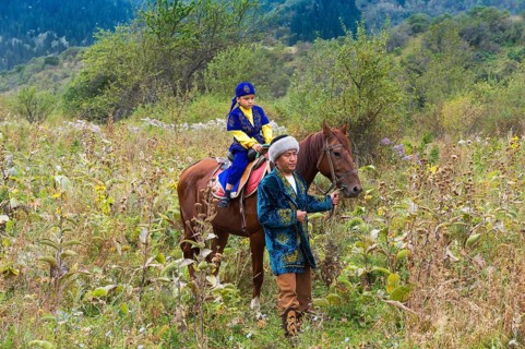 Kazakh man walking around with his son on a horse after Circumcision Sundet Toi ceremony