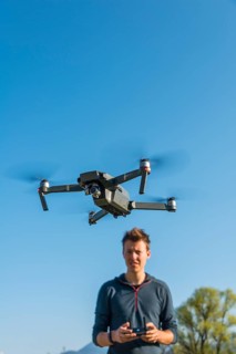 Young man controlling flying quadrocopter