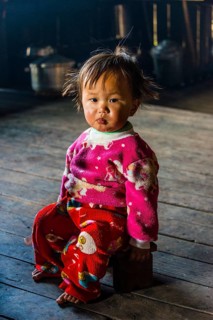 Little girl sits on stool in hut
