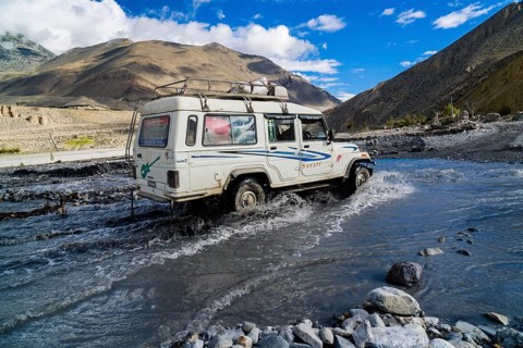 Jeep taxi is crossing a river