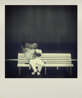 Man reading newspaper on bench