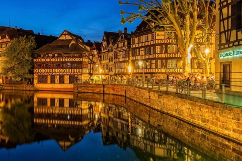 People on a restaurant terrace along the ILL canal at twilight