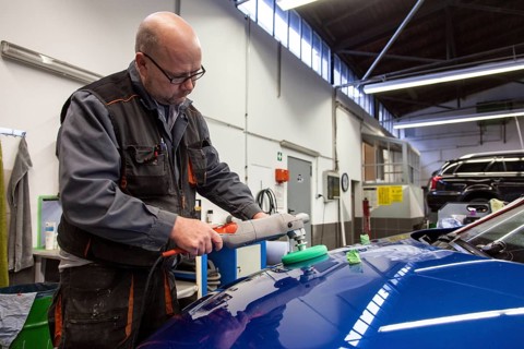 Coachbuilder master with the polishing machine on the car