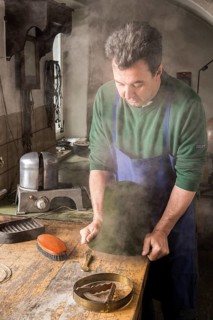 Man fitting wet hat body to wooden form