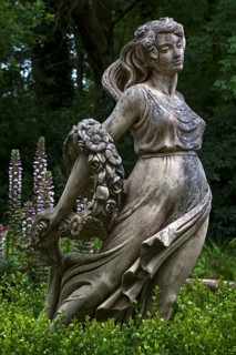 Female sculpture with a band of flowers behind acanthus