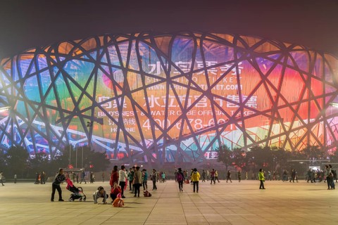 People on square in front of illuminated National Stadium in the Olympic Park