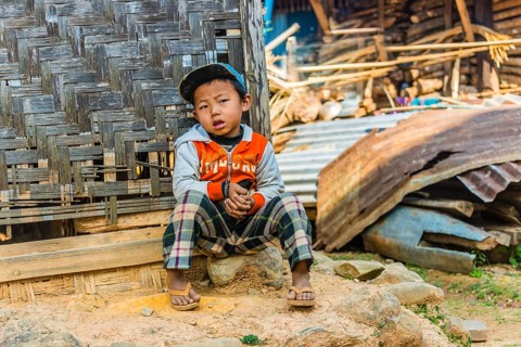 Little boy sitting in front of log cabin