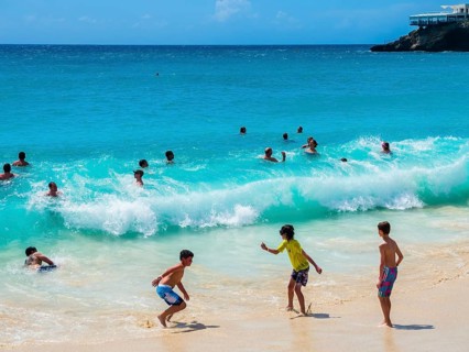Tourists bathing in high waves at Maho Beach