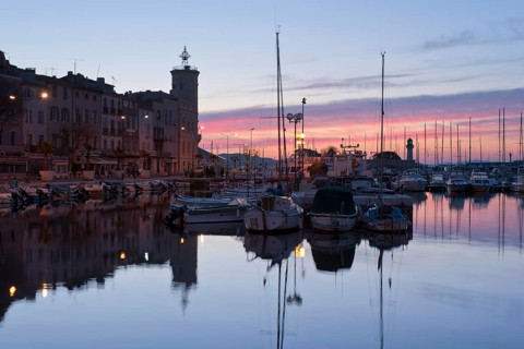 Old city with boats in the harbour at sunrise