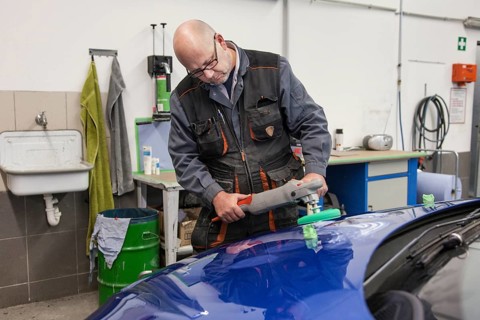 Coachbuilder master with the polishing machine on the car