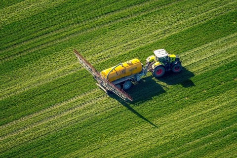 Tractor with pesticide sprayer on meadow