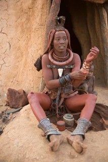 Himba woman with child in front of the hut