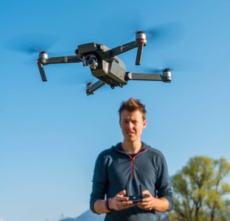 Young man controlling flying quadrocopter