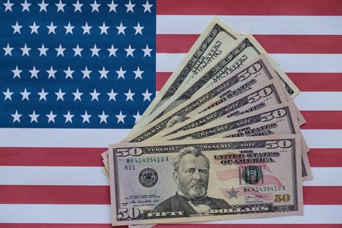 Various US dollar bills on American flag