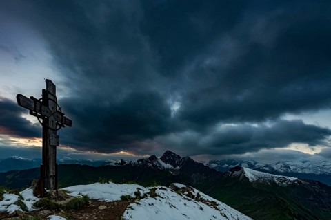 Cross on the summit of Zafernhorn with dark clouds