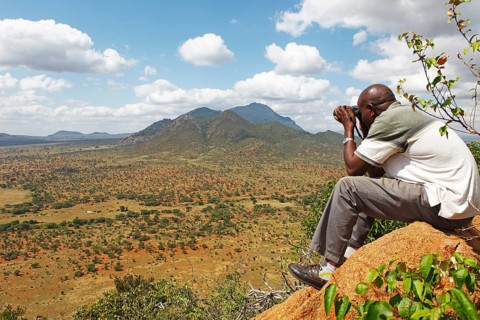 Man with binoculars looking at the Ngulia Hills and the Rhino Valley
